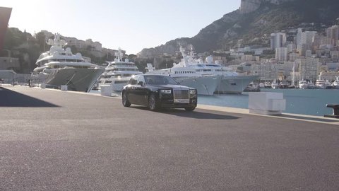 Monte - Carlo, Monaco 28 August 2018 Rolls - Royce Phantom VIII 8 driving in port with city and Yachts at background.