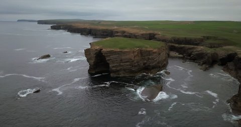 Brown cliffs of a rocky coast of Mainland, largest of Orkney islands, with bluish water of a Norwegian Sea