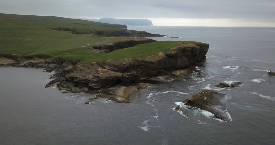 Brown cliffs of a rocky coast of Mainland, largest of Orkney islands, with bluish water of a Norwegian Sea Royalty-Free Stock Footage #1015705483