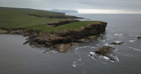 Brown cliffs of a rocky coast of Mainland, largest of Orkney islands, with bluish water of a Norwegian Sea