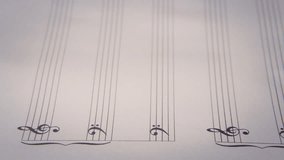 Composing music on a paper sheet with rows and symbols. Detail side shot.
 - Powered by Shutterstock - Get 15% off with code: PIKWIZARD15