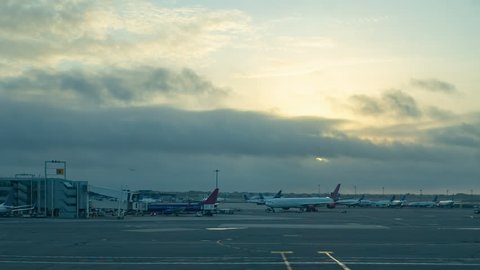 Timelapse of airport runway and terminal at sunrise with planes taxiing and landing, with moving vehicles and lots of activity 
JFK airport New York
