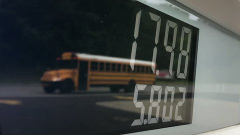 A detailed close-up view of a gas pump's meter with traffic passing by in the reflection.	