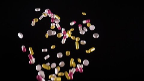 a variety of pills fly up and fall. Side view. Slow motion