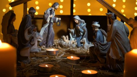 Jesus Christ Nativity scene with atmospheric lights and candles. Jesus Christ birth in a stable with Mary and Joseph figures. Christmas scene. Dolly shot 4k