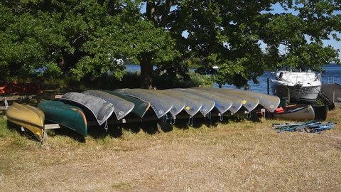 Pataholm, Sweden – June 28, 2018: Aluminum Canadian canoes in a row on land in coastal landscape on a windy and sunny summer day.