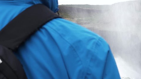 man with blue jacket looking at big waterfall, gulfoss waterfall golden circle iceland