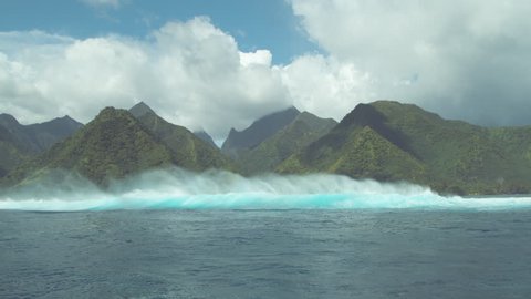 SLOW MOTION: Beautiful ocean waves approach the vivid green mountains of the lush island in the Pacific. Spectacular view of a big turquoise swell rushing towards a remote tropical island before storm