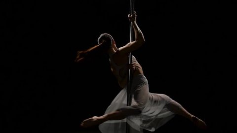 Female dancer performs sexy poledance on pole . Black background. Slow motion