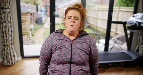 4K Funny unfit woman straining to lift small weights & pulling faces to camera