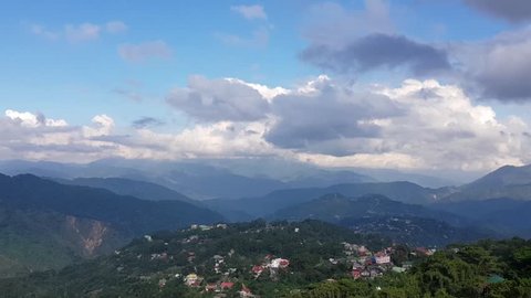 A pan of a village in the mountains. The shot features thick clouds and a feeling of breeze. Shot in Baguio, Philippines.