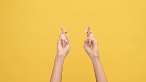Woman hands praying with crossed fingers and rejoice after that over yellow background