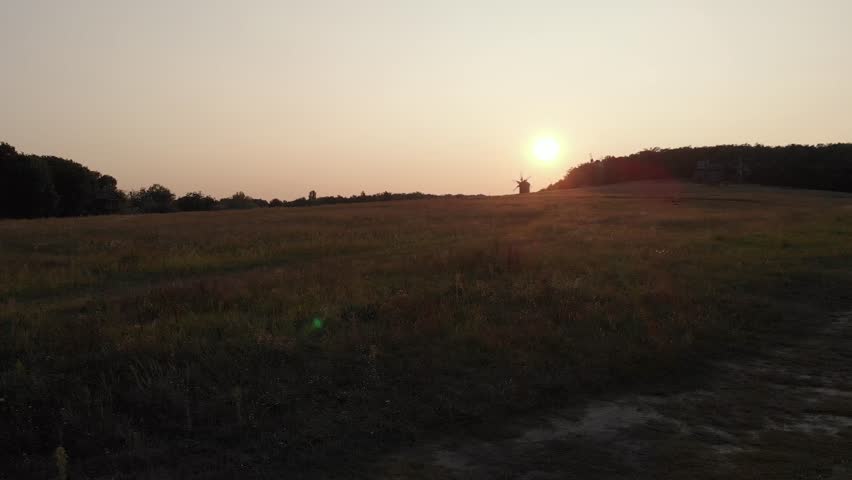 Shooting in the field at sunset in September. In the background of the mill. Shooting from a drone.