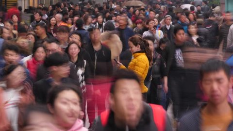 SHANGHAI - MARCH 18, 2018: Unidentified Asian people fuss around, woman (model released) stay still, stare to smartphone. Time lapse shot of busy and crowded Nanjing Road