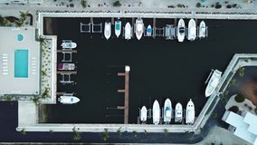 Drone video flying straight down to a dock in a marina with boats and a pool in the Florida Keys Atlantic Ocean
