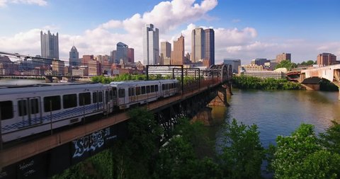 PITTSBURGH - Circa May, 2017 - A daytime aerial establishing shot of the early evening Pittsburgh skyline as a subway train travels in the foreground.	