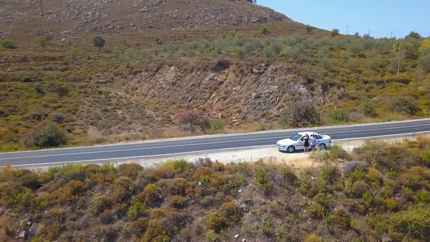 People traveling, road trip on curvy road through sunny summer. Road to Bozburun Village on the rocky mountain, car parking on the way, passengers looking at beautiful view with high peaks at background