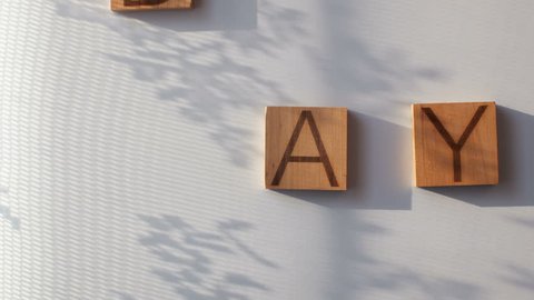 The word "DAY" is laid out in wooden letters