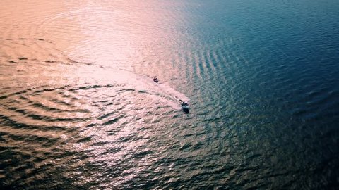 4K Overhead Aerial Shot Of A Speed Boat Pulling A Tube With People Through The Blue Waters Video de stock