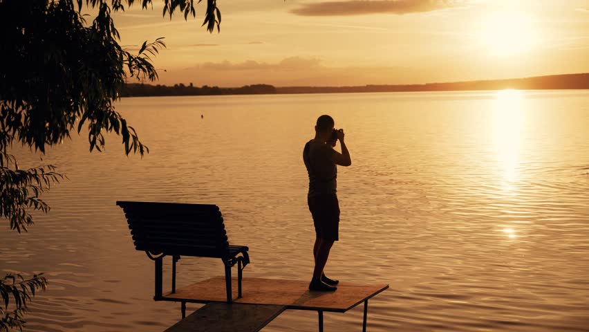 Photographer taking picture of sunset at local beach which is tourists point. Beautiful summer sunset.