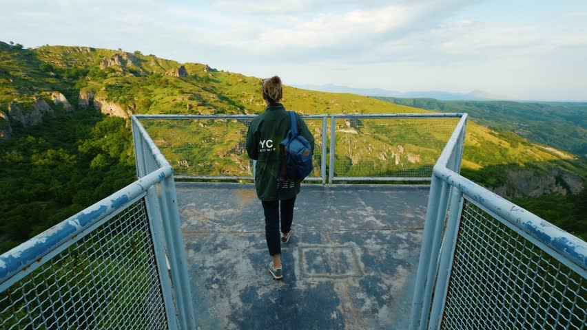 Young woman on observation deck with greate view on mountain ridge at sunset time