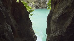 Peeking through an eroded tunnel beneath a natural. limestone. karst tower formation reveals an exotic. tropical lagoon in southern Thailand. Ultra HD stock footage