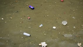 Plastics and other rubbish float in the shallow sea water beneath a poor fishing village in southern Thailand. Ultra HD stock footage