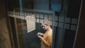 A view of young confident successful businesswoman riding down in transparent elevator using smartphone e-commerce app. - Powered by Shutterstock - Get 15% off with code: PIKWIZARD15
