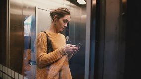 A view of attractive stressed busy Caucasian woman riding up in transparent elevator using smartphone mobile office app. - Powered by Shutterstock - Get 15% off with code: PIKWIZARD15