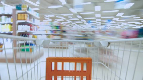 Time Lapse of the Shopping Cart Moving Between Various Aisles and Section in the Big Supermarket. Inside Trolley Various Healthy Items and Convenience Food. Shot on RED EPIC-W 8K Helium Cinema Camera.