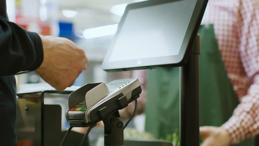 In the Supermarket Close-up Footage of the Man Paying with Smartphone at the Checkout Counter. Using Modern and Convenient Wireless NFC Paying System in Big Mall. Shot on RED EPIC-W 8K Helium Camera. Royalty-Free Stock Footage #1015776454