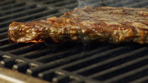 Slow motion of a large beef sirloin steak grilled on a charcoal grill Video Stok