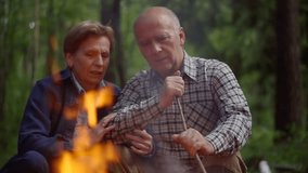elderly couple is resting in hiking camp near fire, woman is hugging her beloved husband - Powered by Shutterstock - Get 15% off with code: PIKWIZARD15