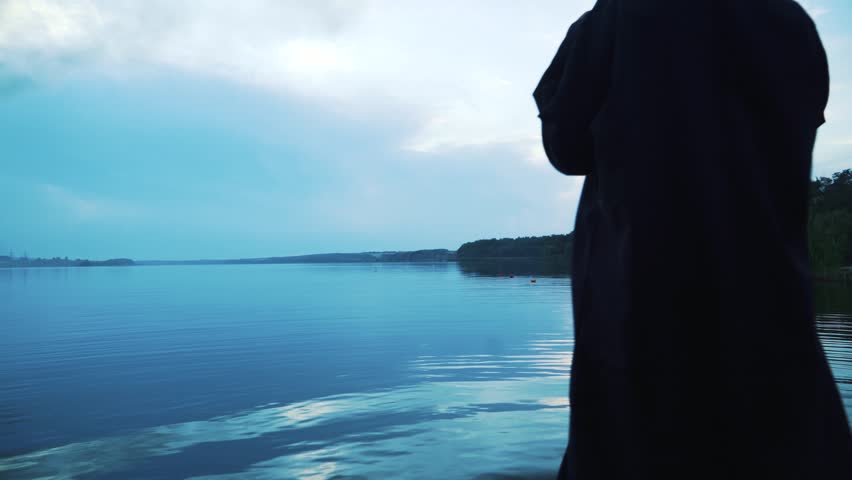 Scary figure in black mantle in the river. Halloween costume.