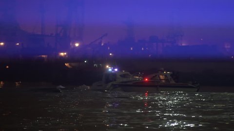A police boat is looking for criminals in the port at night. Concept of the work of the rescue service on the water
