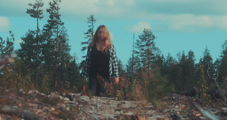 A girl with a basket in her hands walks through the forest.