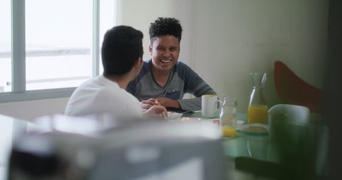 Homosexual couple, gay people, same sex marriage between hispanic men. Male partners eating breakfast at home and using toaster