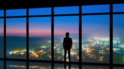 The man standing near panoramic windows on the foggy city background. time lapse