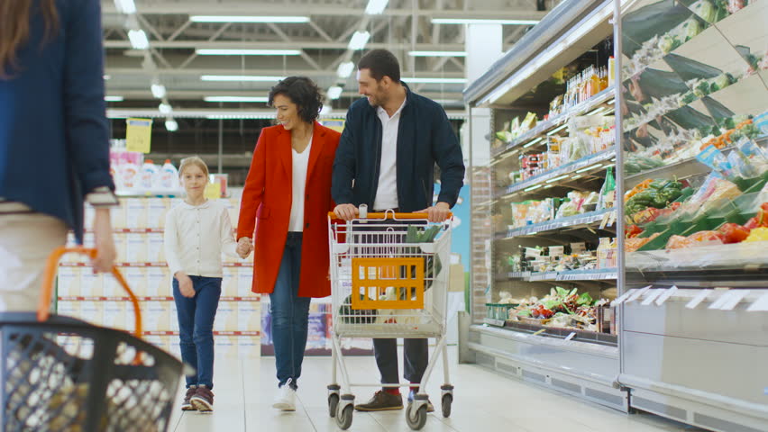 At the Supermarket: Happy Family of Three, Holding Hands, Walks Through Fresh Produce Section of the Store, Holding Hands. Father, Mother and Daughter Having Fun Time Shopping. Shot on RED EPIC-W 8K. Royalty-Free Stock Footage #1015805185
