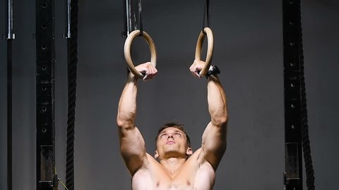 strong bodybuilder muscular athletic man with jump rope and gymnastic rings pumping up muscles workout bodybuilding concept background - muscular bodybuilder handsome men doing exercises in gym naked 