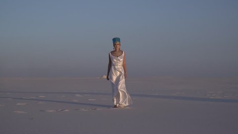 The great queen of Egypt walks through the desert at sunset, slow motion