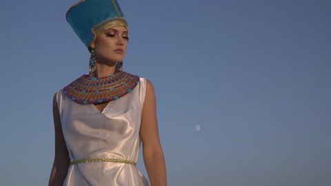 The majestic queen of Egypt stands in the background of the moon and looks around, slow motion