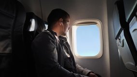 The young man looks out the window of the plane in the evening. He listens to the headphones and rests. - Powered by Shutterstock - Get 15% off with code: PIKWIZARD15