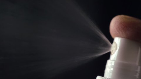 Slow motion of spray bottle drops on black background. Male perfume bottle on a dark background
