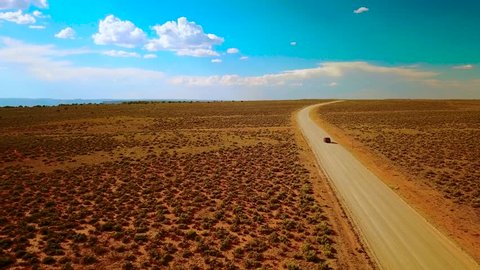 Aerial tracking shot of an SUV on a desolate desert road