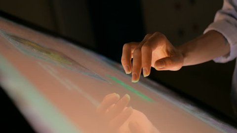 Woman using interactive touchscreen display at modern museum. Education and technology concept