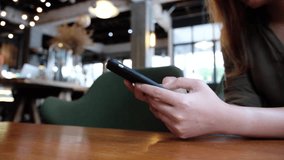 Slowmotion video of a woman's hand holding and typing on smart phone in modern white cafe 