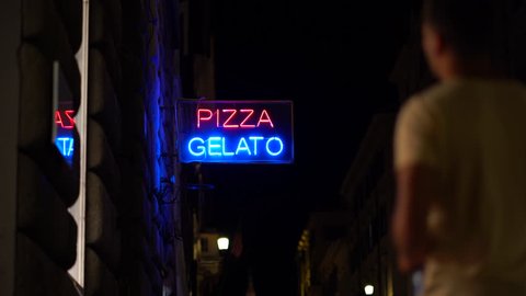 Light neon sign "Gelato Pizza" outside in night city. Italian Ice cream vendor advertisement.