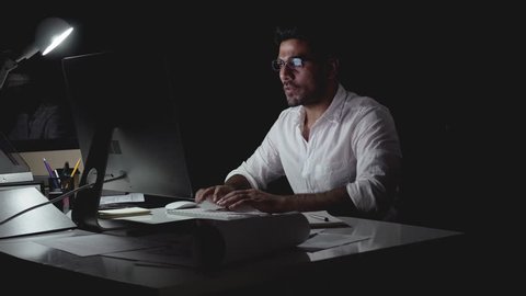 Dedicated Asian businessman seriously working on computer late at night in the office
