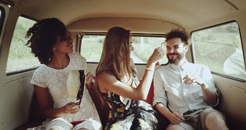 Two young women and one man inside of retro bus spending nice time together smiling faces wearing boho style clothes. Slow Motions Vídeo Stock